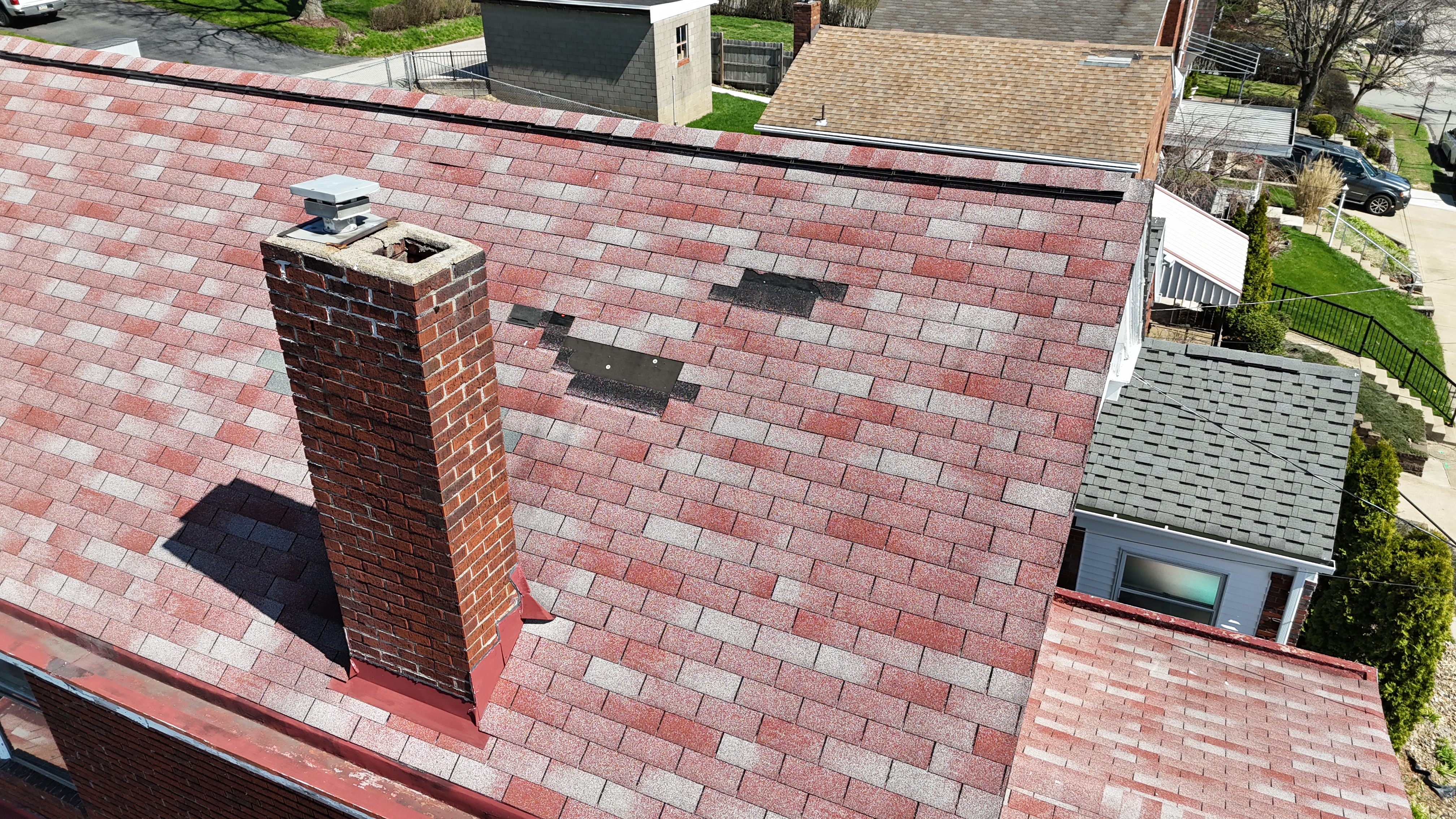 Roofing technician inspecting roof flashing with clipboard